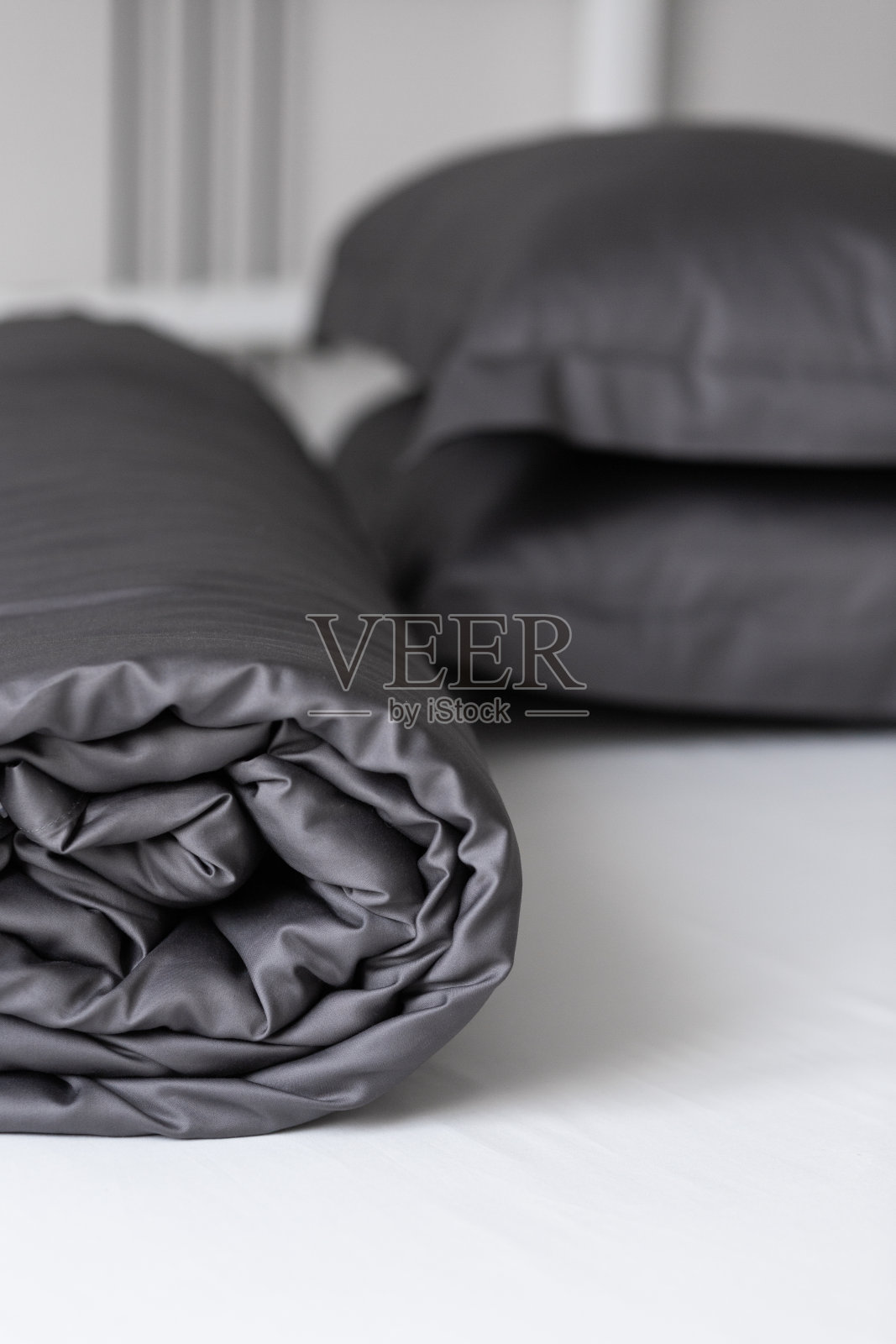 睡了一夜的空床。深灰色缎面床上用品:莱赛尔、真丝、涤纶。把床弄脏。北欧室内照片摄影图片