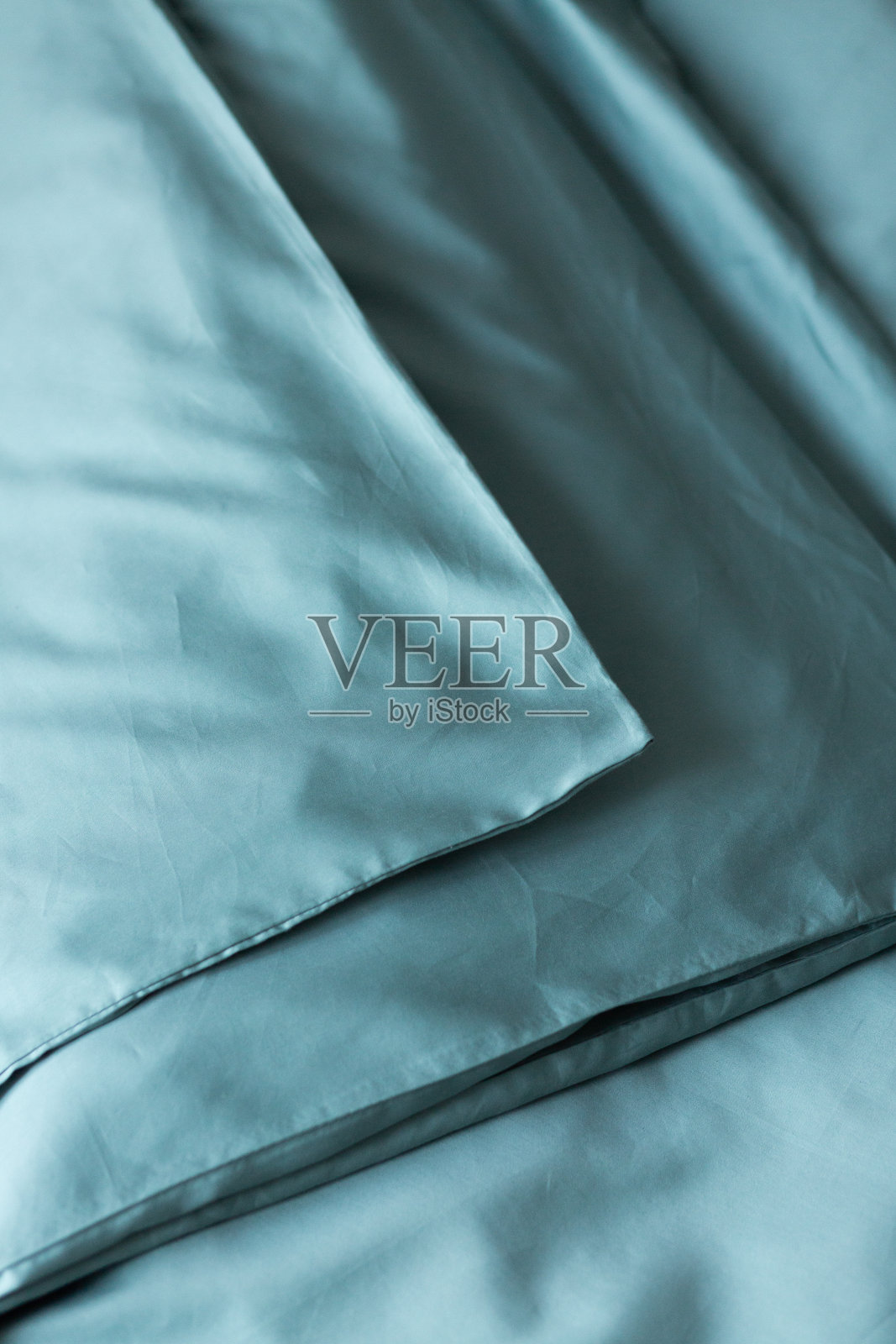 绿松石缎面羽绒被，床上有纽扣:莱赛尔，丝绸或聚酯。家纺。关闭了。背景。照片摄影图片