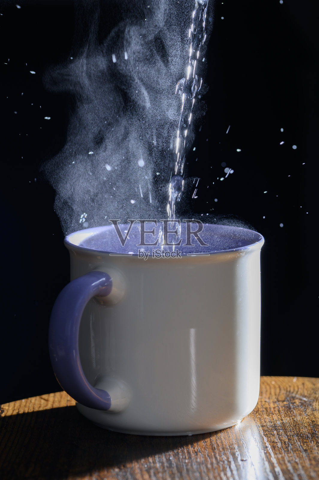 水壶里的一股开水流进瓷杯里。照片摄影图片