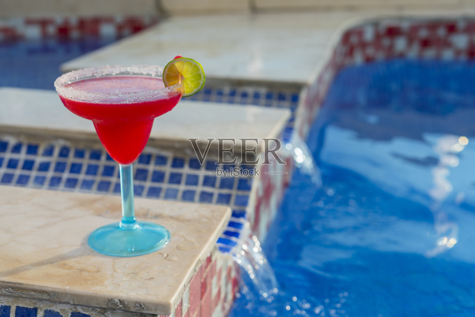 在卡塔赫纳一家酒店的游泳池旁边，有一个装有白酒鸡尾酒的玻璃杯照片摄影图片
