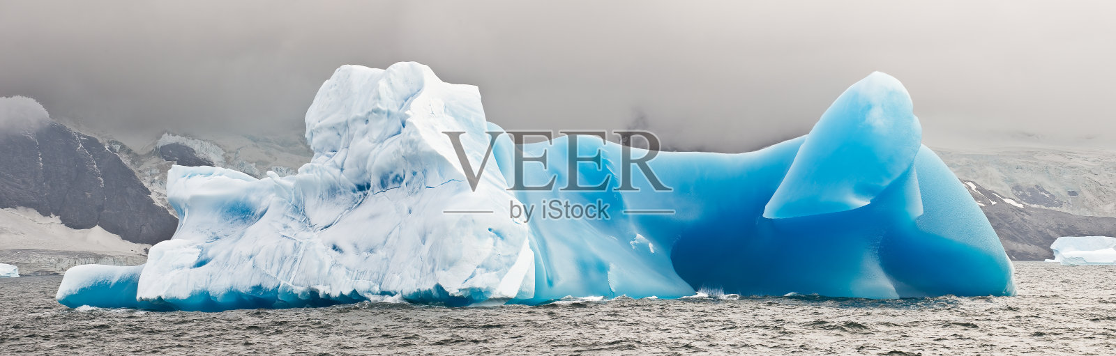 南奥克尼岛Shingle湾附近的蓝色冰山。在大气压力下结冰的冰有一个不寻常的特性，那就是固体的密度比液态水低大约9%。冰山是一大块断裂的淡水冰照片摄影图片