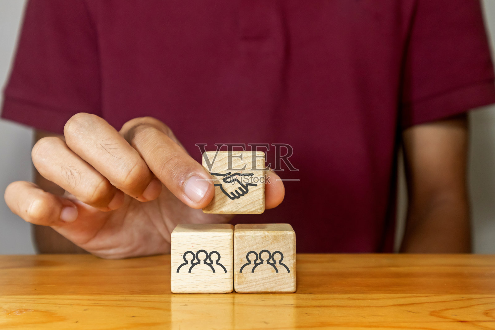 男子手持木块与一群人握手图标。合作，团队合作，伙伴关系或商业交易的概念。照片摄影图片