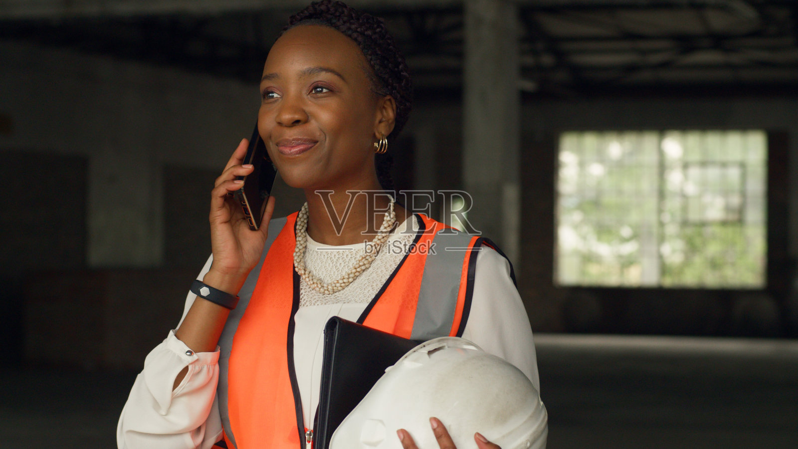 微笑的女建筑师戴着安全帽在工地打电话照片摄影图片