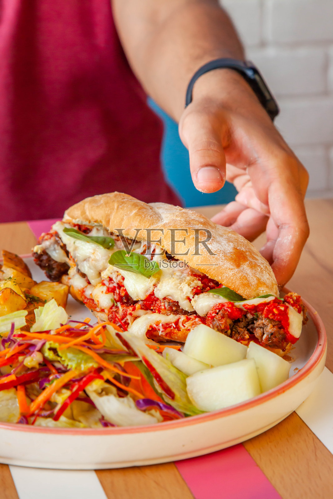 肉丸子三明治夹在法棍面包里，在咖啡馆里享用，配上sautsamd蔬菜，男性的生活方式。照片摄影图片