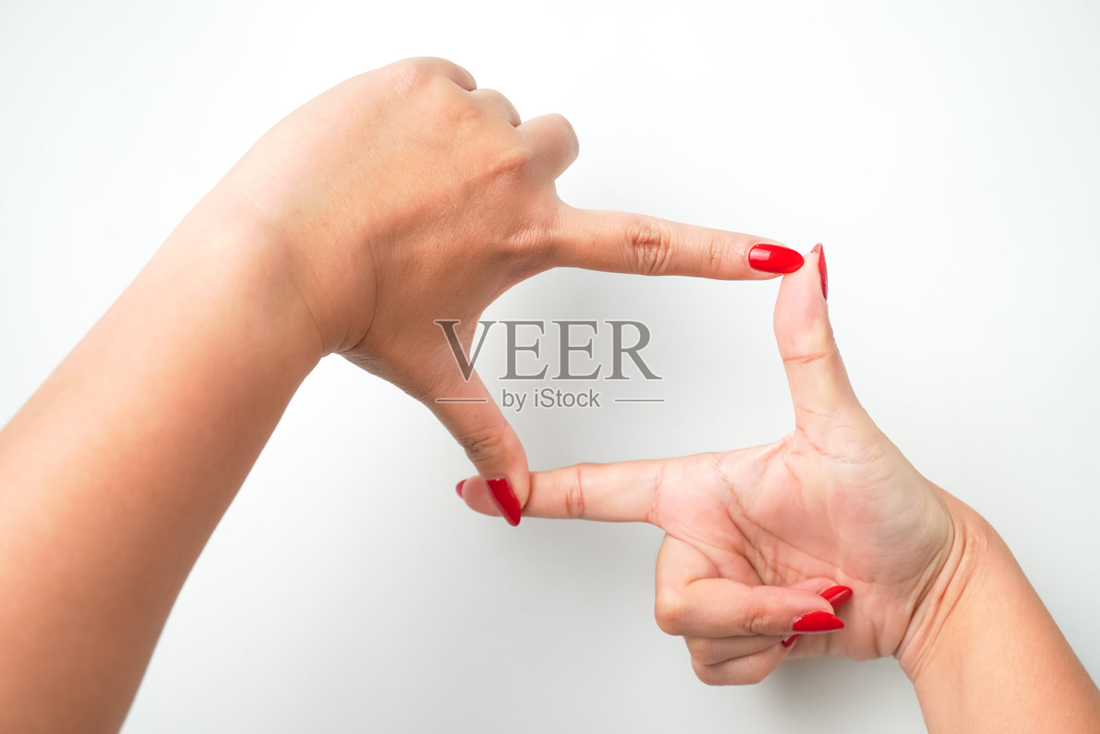 涂着鲜红色指甲油的女性用食指和拇指形成一个方形的手势。拍照或取景的概念。照片摄影图片