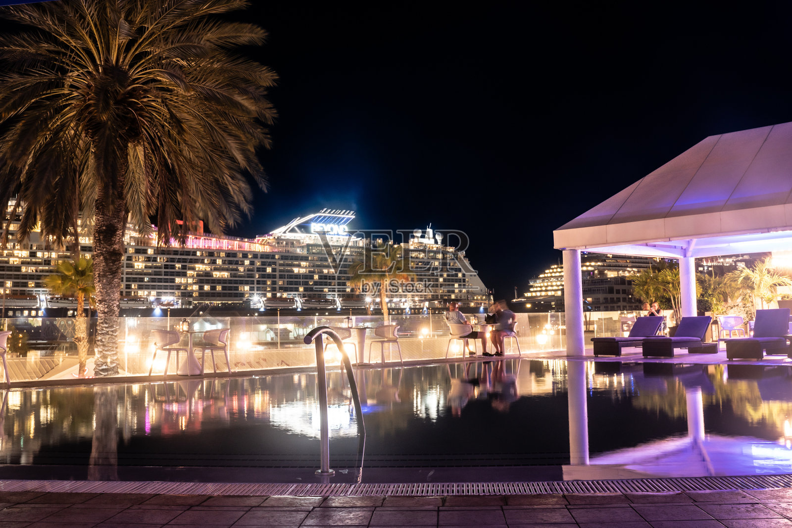 从阿鲁巴奥兰杰斯塔德市的夜景，游客、棕榈树和停靠在港口的游轮。照片摄影图片