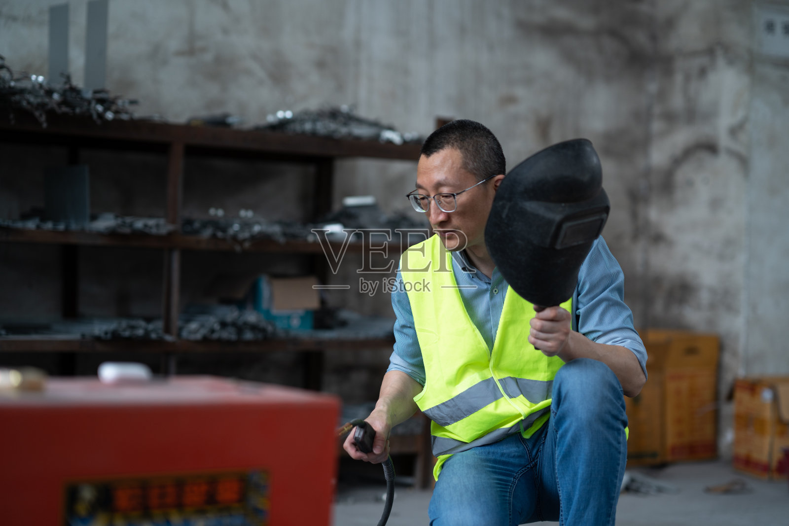 中年男人手拿电焊工具车间里干活照片摄影图片