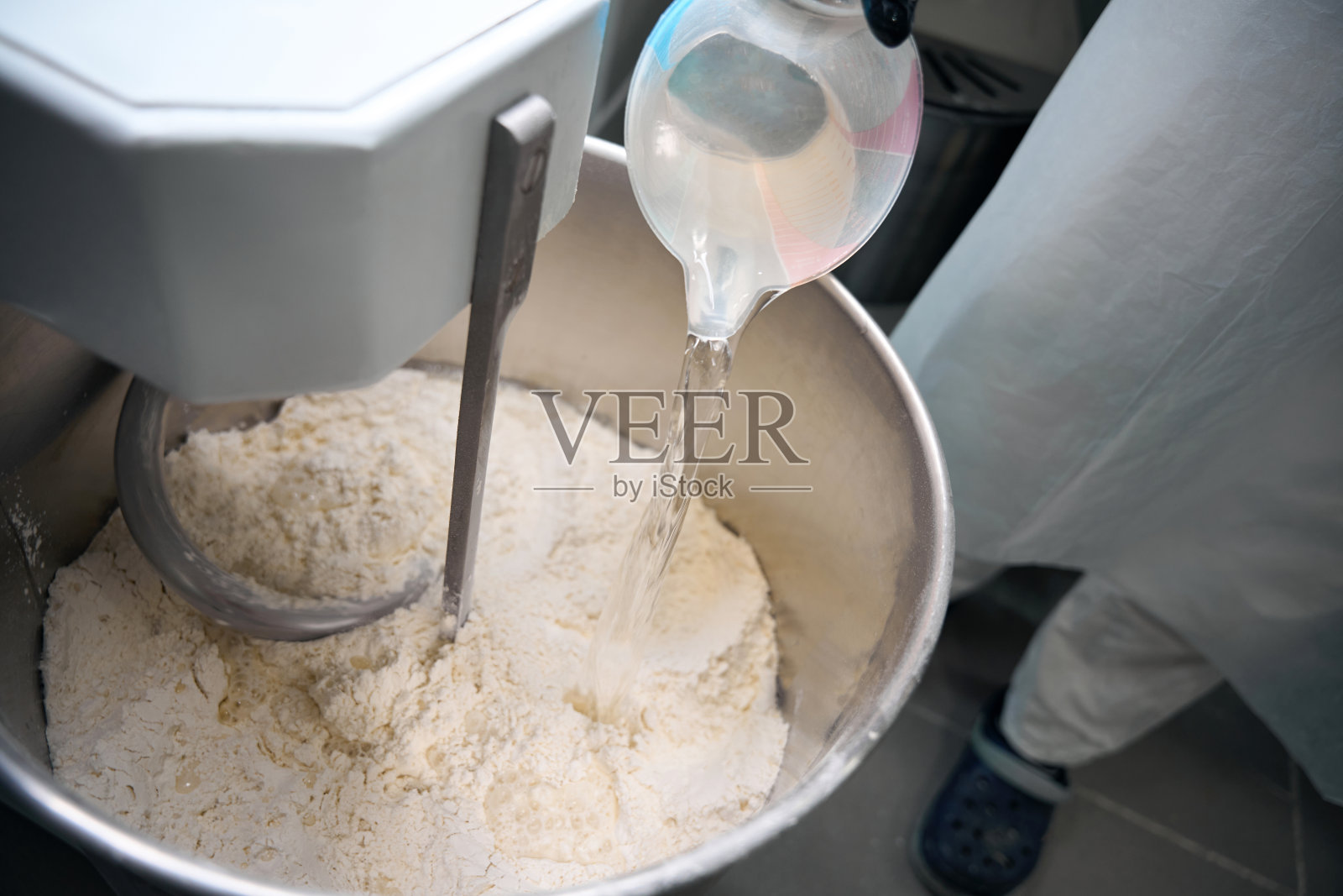 穿制服的工人把水倒进和面机照片摄影图片