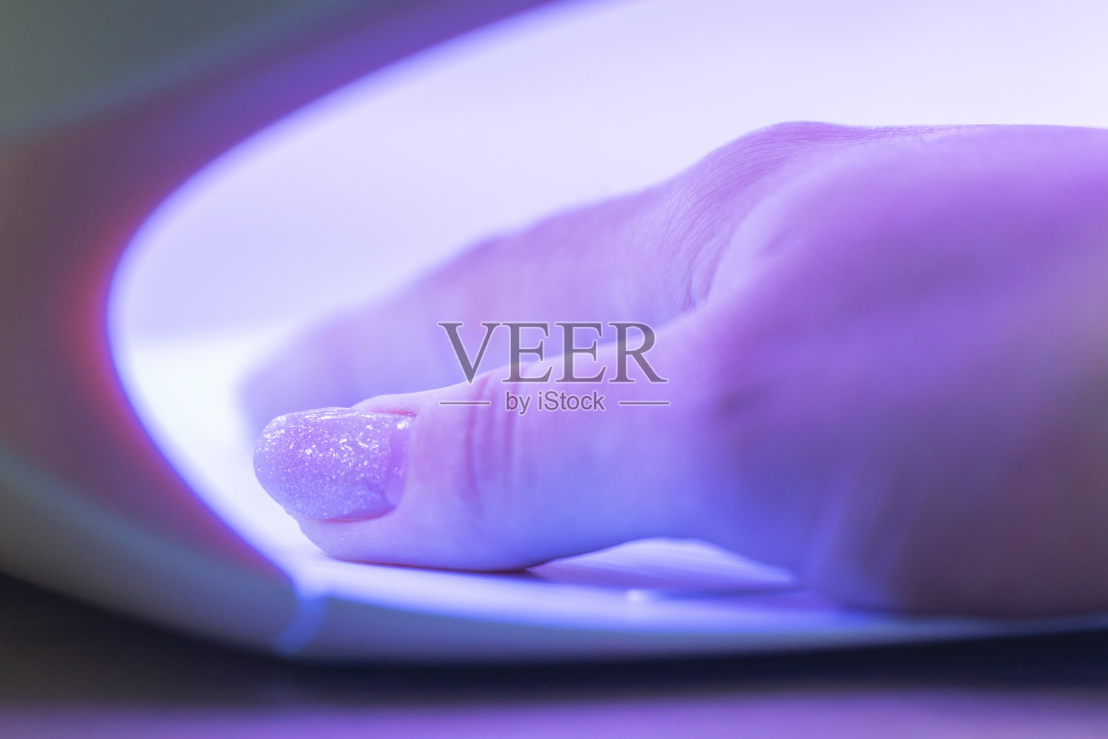 女孩用紫外线灯擦干涂有指甲油的指甲照片摄影图片