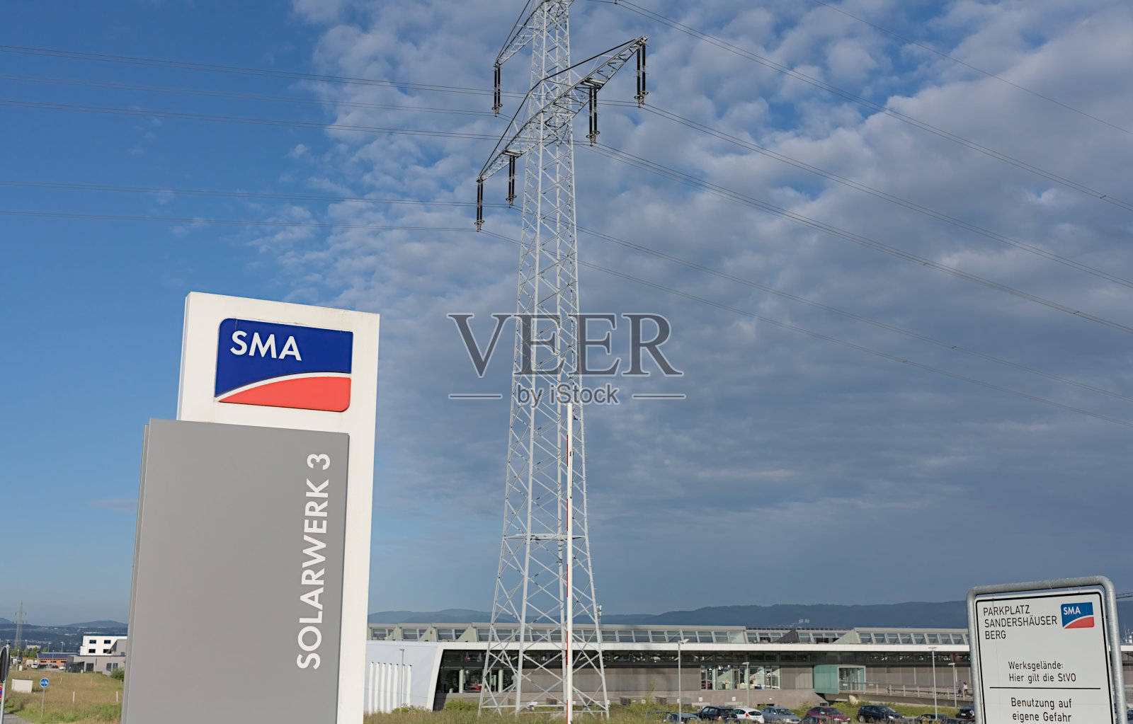 带有SMA Solar Technology AG标志的支柱，带有Solarwerk 3和高压塔照片摄影图片