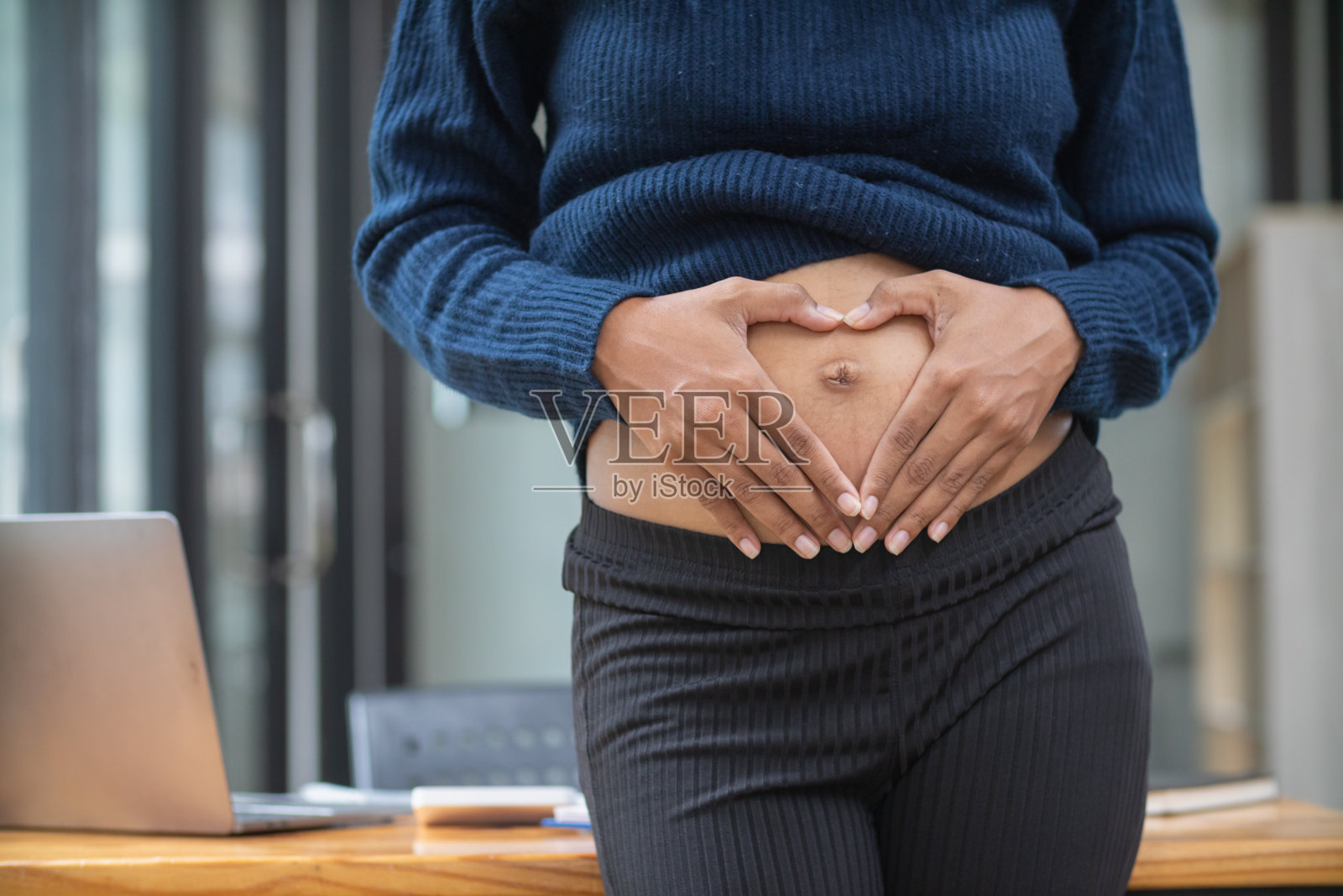 怀孕的妈妈用手抚摸自己的肚子，用温柔和爱来安慰子宫里的宝宝。一位准妈妈用她的手温柔而慈爱地抚摸着她的肚子。照片摄影图片