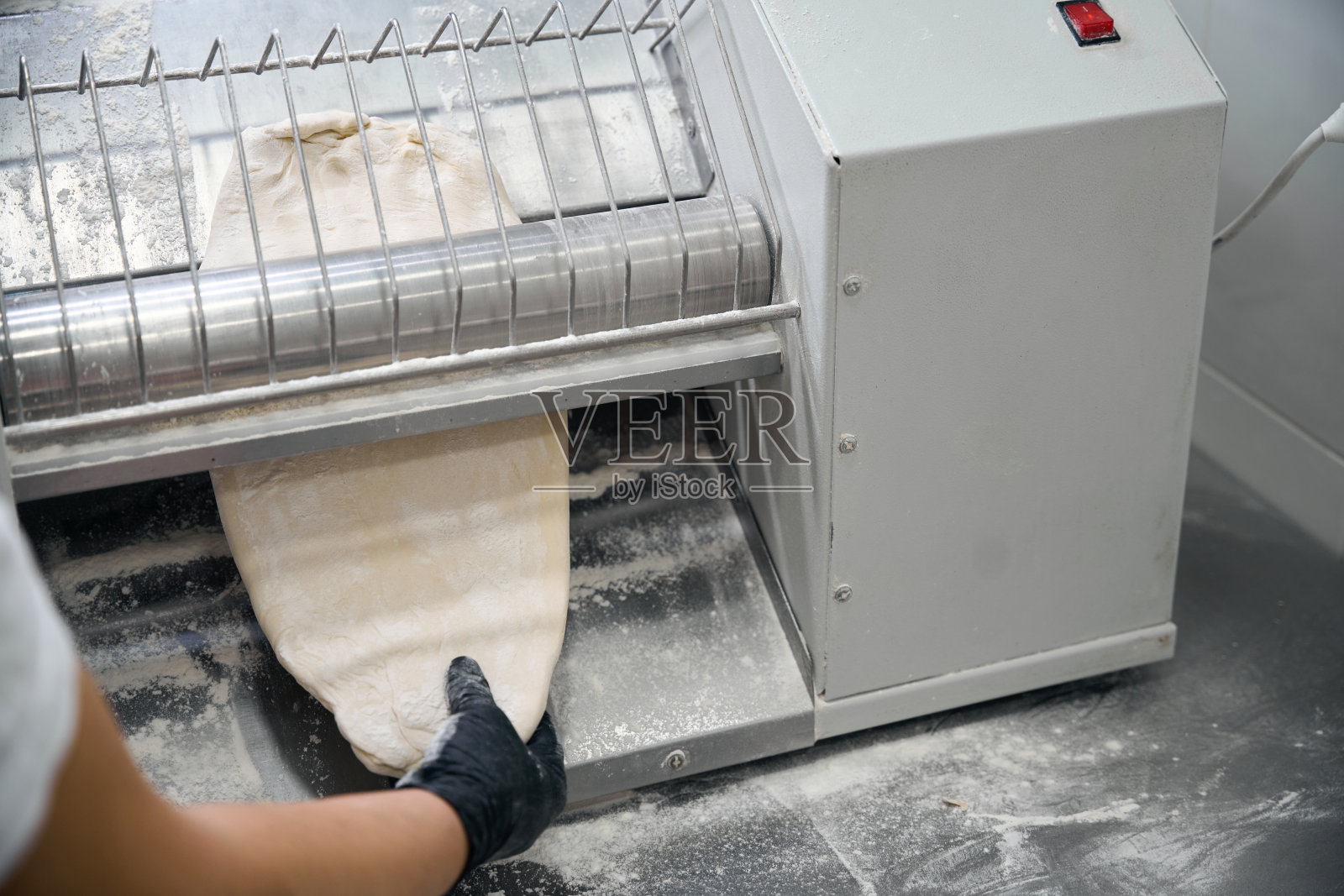 厨房工人将一部分生面团放入薄片机照片摄影图片