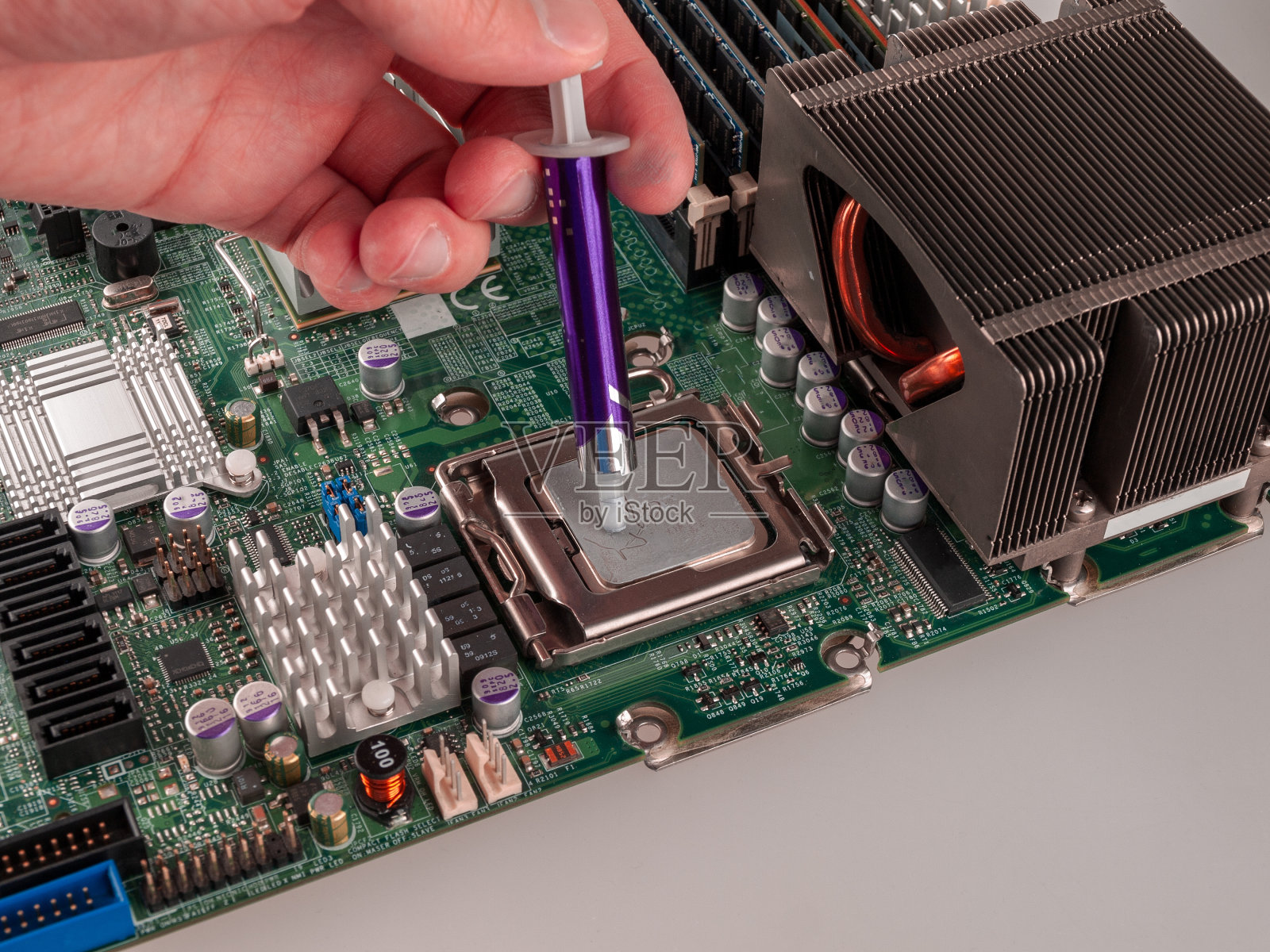 在安装散热系统的散热器之前，在计算机或服务器电路的外壳上正确地涂抹导热膏照片摄影图片