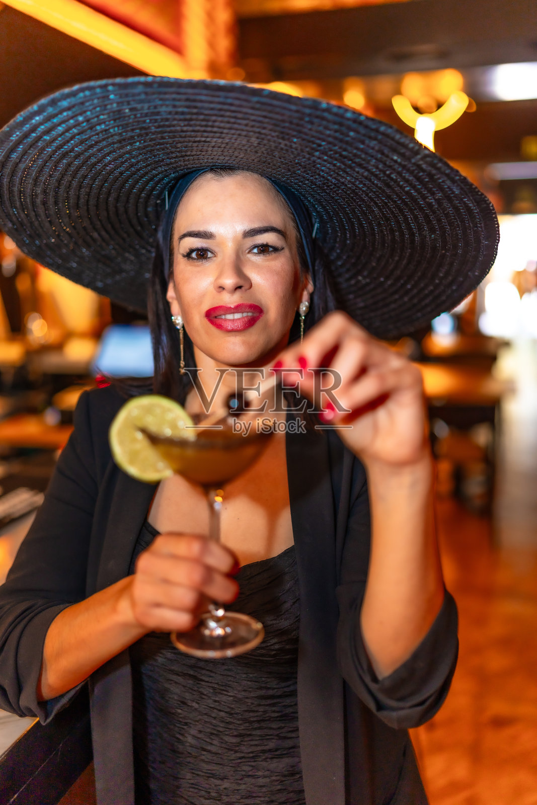 优雅的女子用马提尼酒杯喝鸡尾酒照片摄影图片