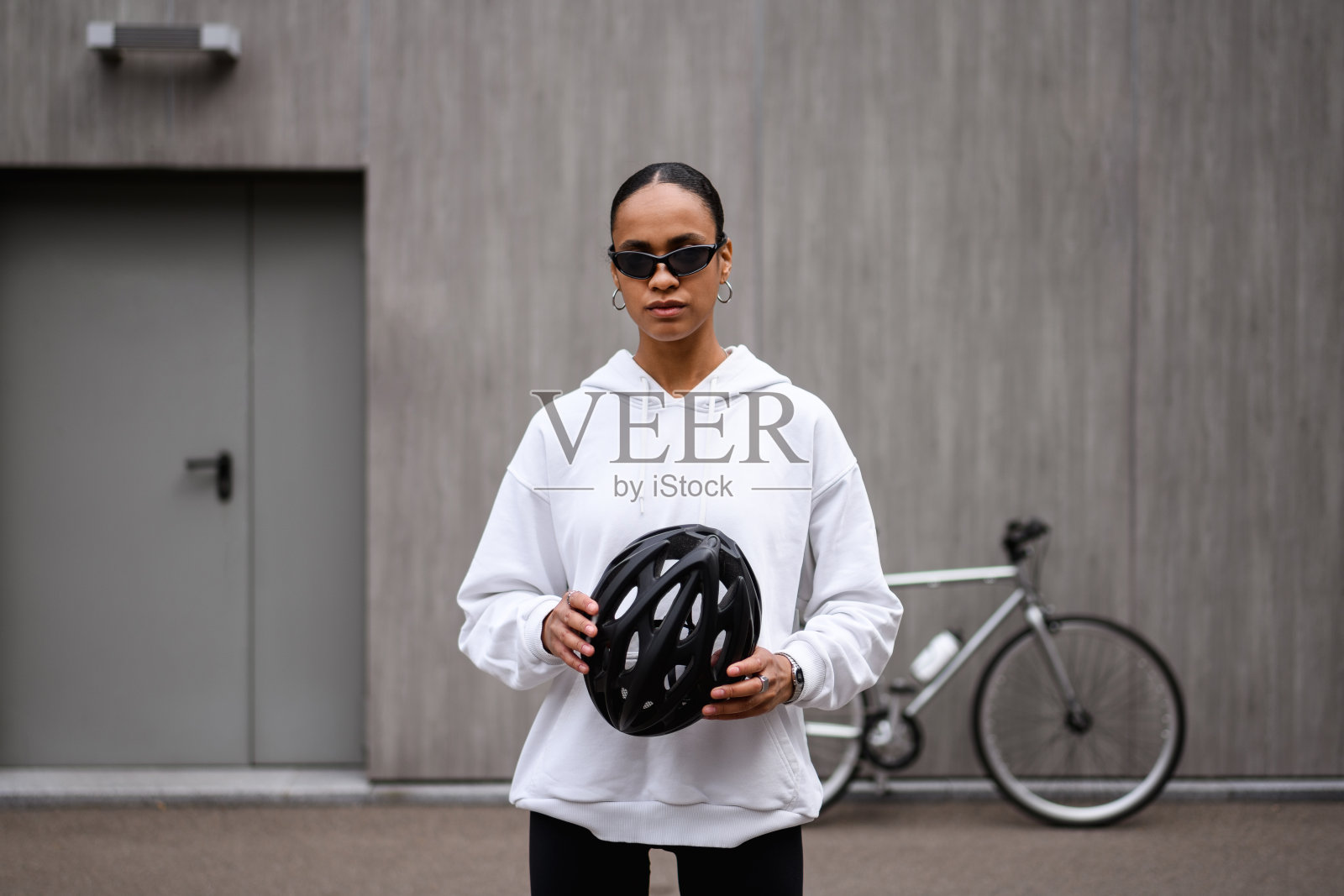 时尚的非裔美国自行车手拿着安全头盔在街上照片摄影图片