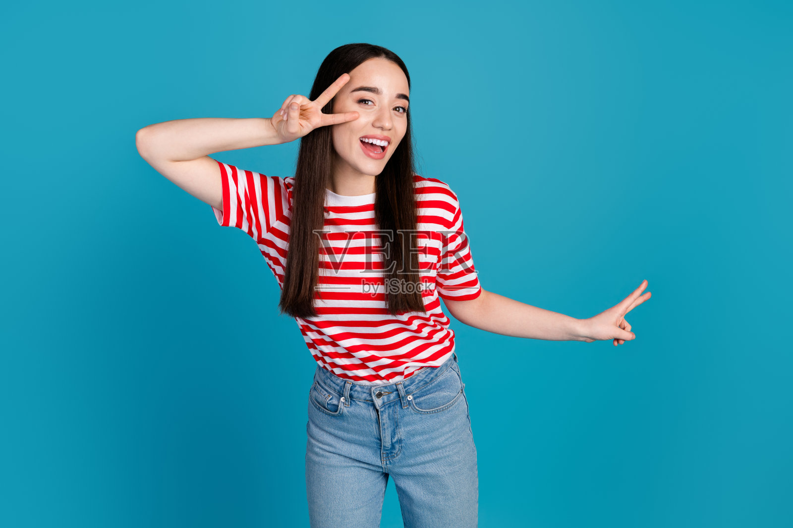 照片中可爱可爱的女孩穿着印有v字的条纹t恤，空白的空间孤立的蓝色背景照片摄影图片