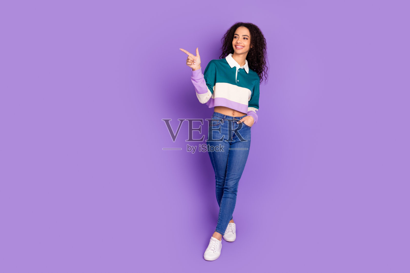 可爱的年轻女孩的全身肖像直接指空空间穿衬衫孤立在紫色的背景照片摄影图片