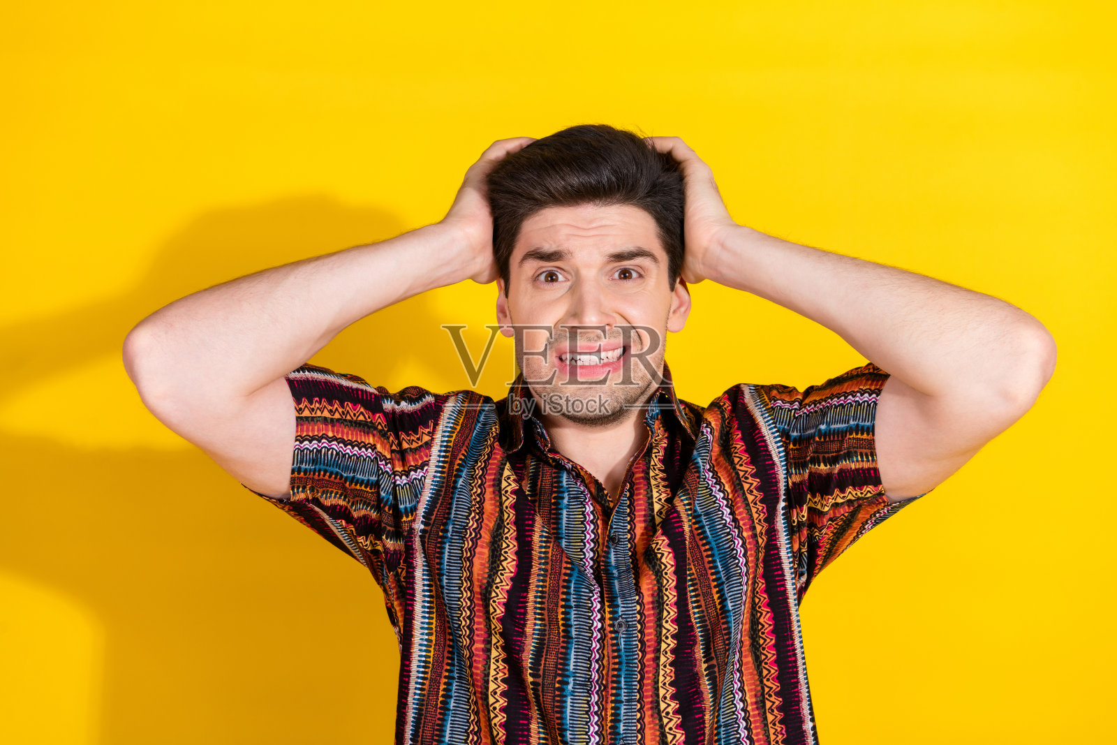 漂亮的年轻人的照片，手臂触摸头部，穿衬衫孤立的黄色背景照片摄影图片