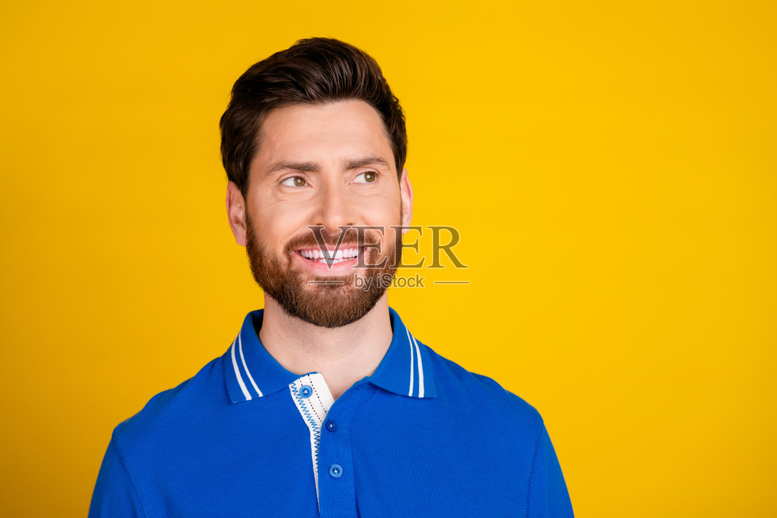 照片上有魅力的年轻人看起来空无一人，笑容灿烂，穿着时尚的蓝色衣服，孤立在黄色的背景上照片摄影图片