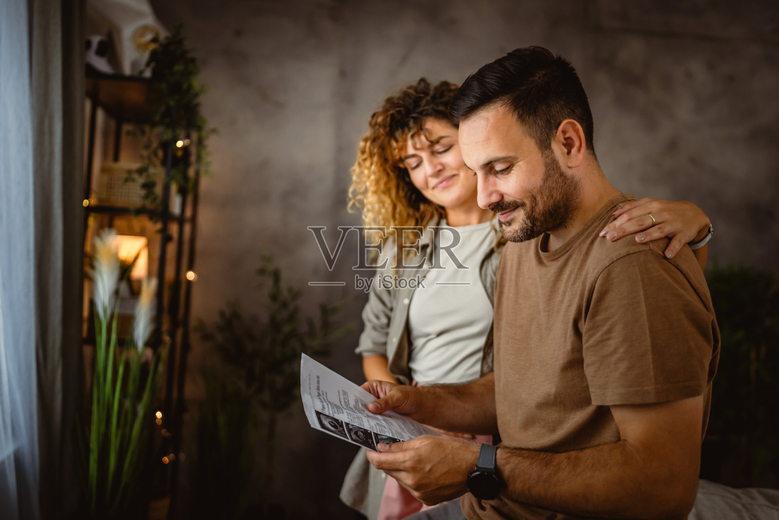 妻子抱着丈夫看孩子的超声波照片照片摄影图片