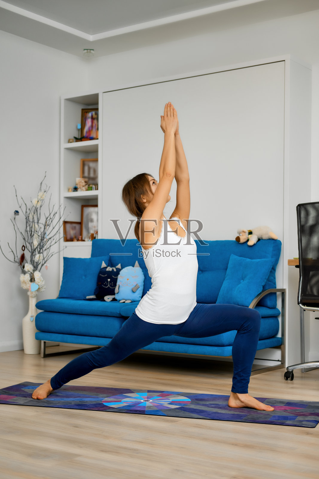 年轻女子在家里练习瑜伽，站在一个姿势照片摄影图片
