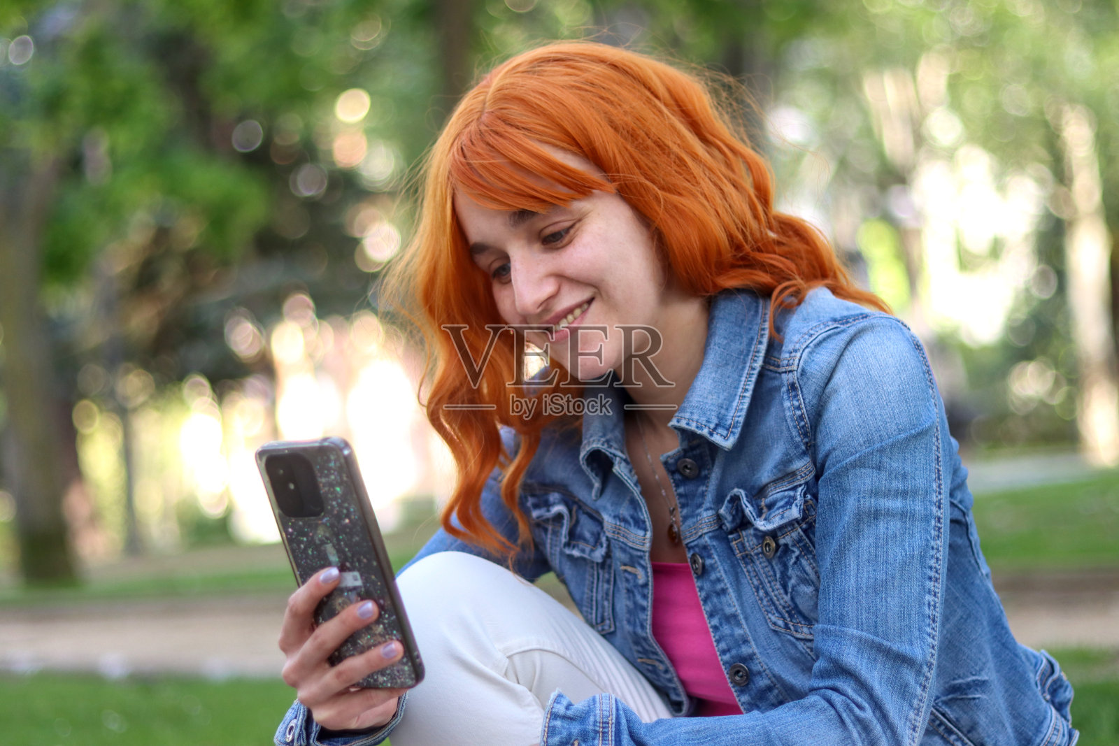 年轻的红发女人拿着手机坐在前面照片摄影图片