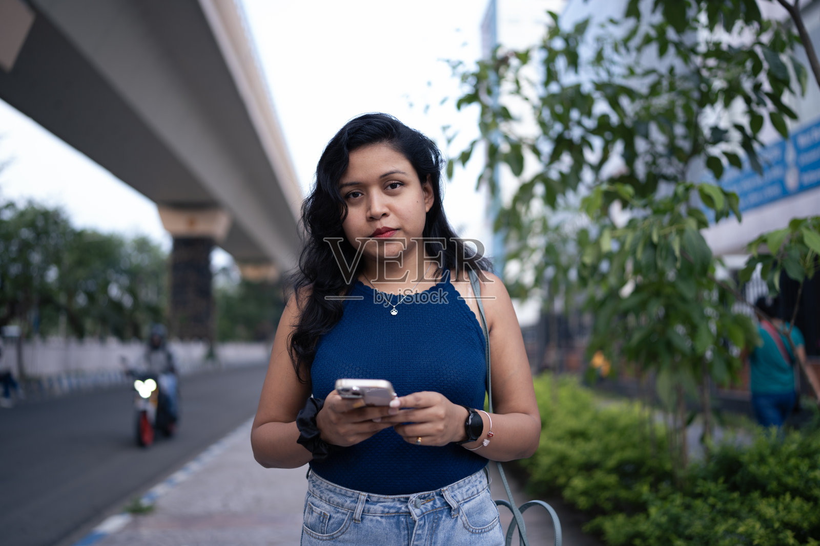 自信的年轻女子在城市街道上拿着智能手机照片摄影图片