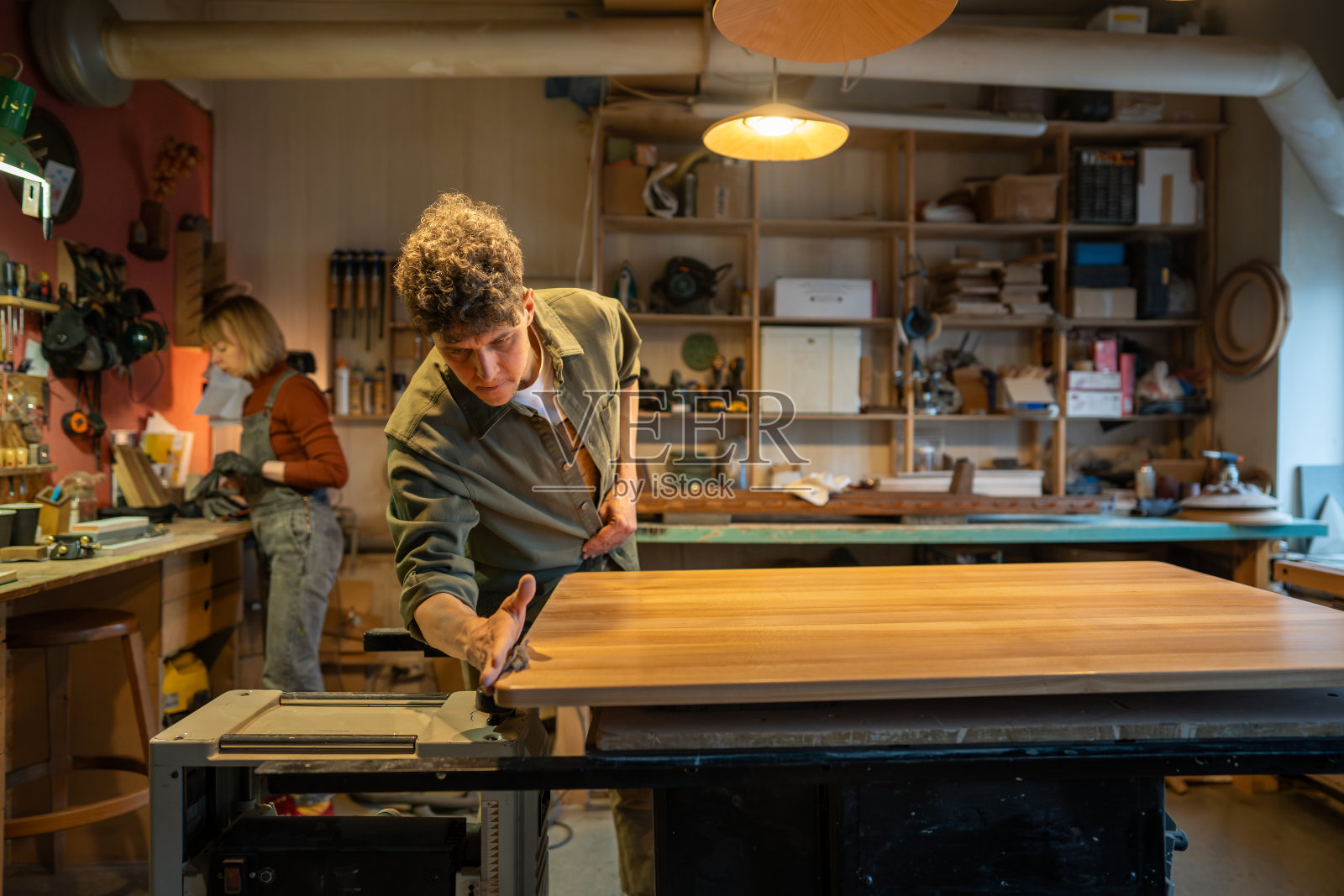 木工车间，专业工匠工作。男木匠师傅用桌子的表面工作照片摄影图片