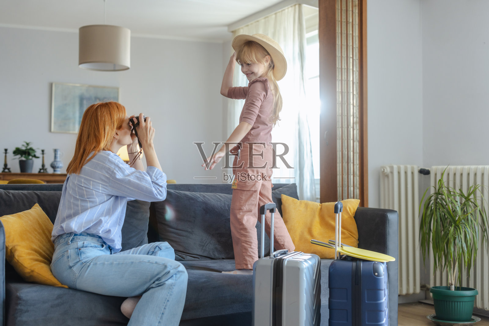 母女俩收拾行装，在家里玩得开心。一个小女孩正在摆姿势拍照照片摄影图片