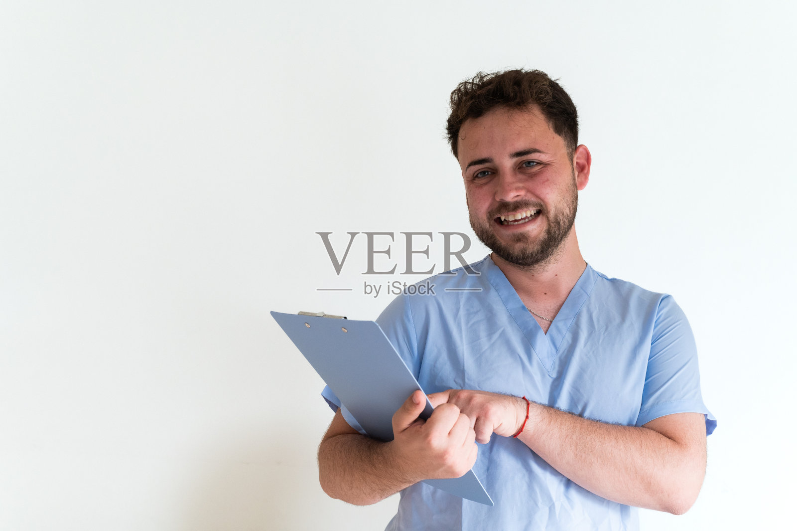 年轻自信的医生面带微笑，手里拿着白底的写字板照片摄影图片