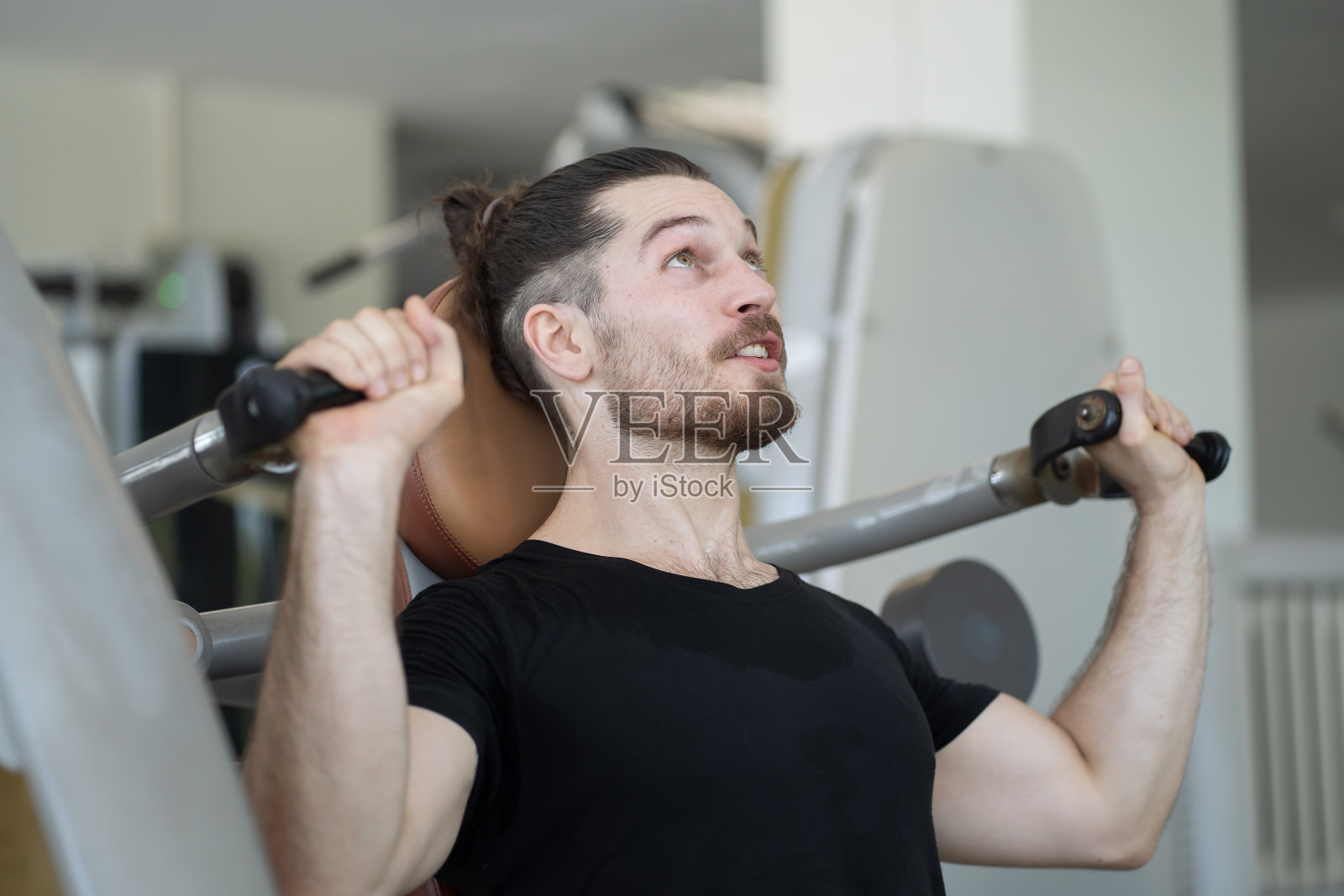男运动员在健身房进行力量训练时使用健身器。男子在健身房使用健身器进行锻炼。运动健身概念照片摄影图片