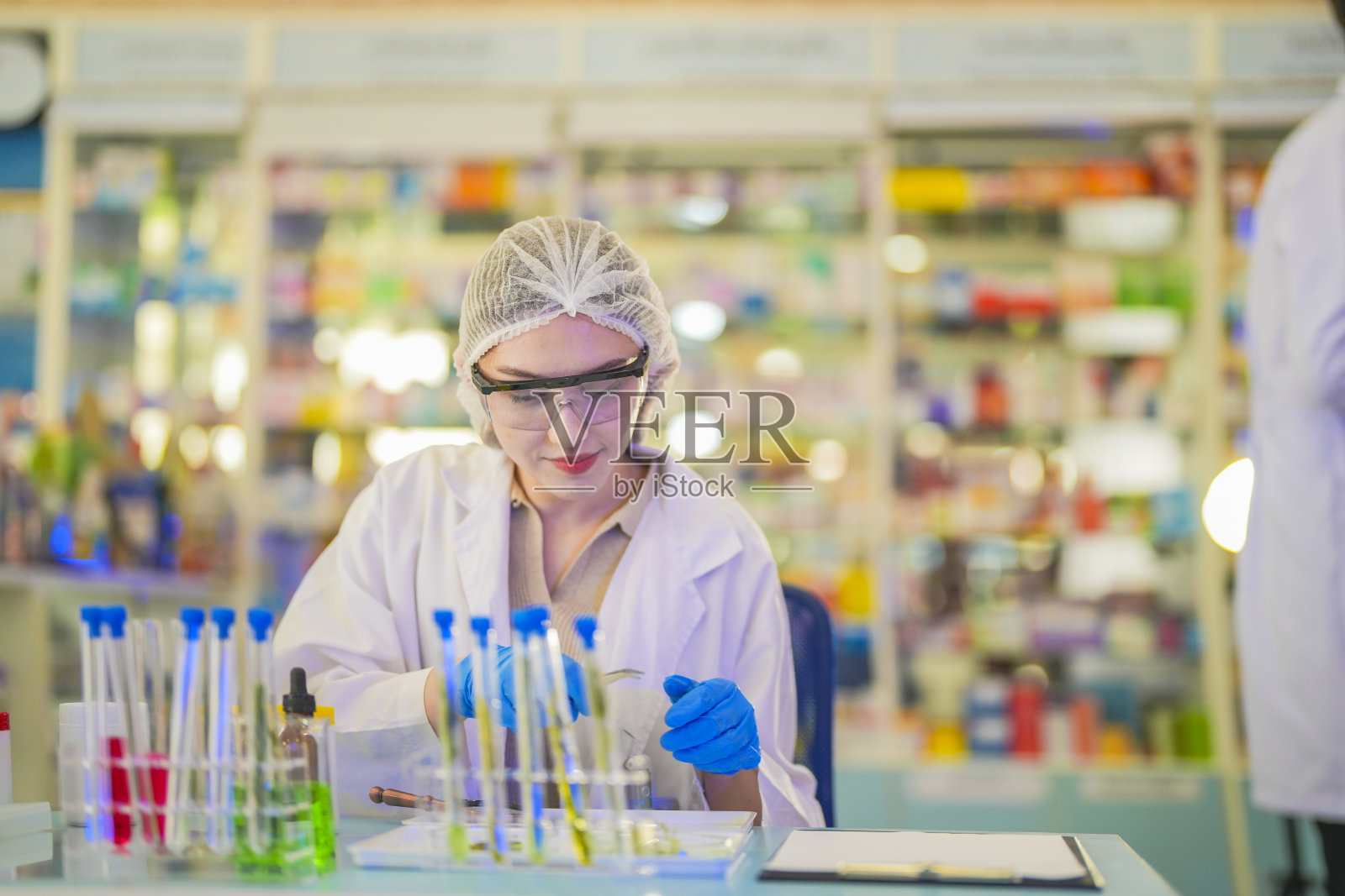 女科学家通过试管进行化学液体和植物样本的实验。在一个实验室里，在一个现代化的实验室里，通过安全、干净的测试，把测试样本放在后台。照片摄影图片