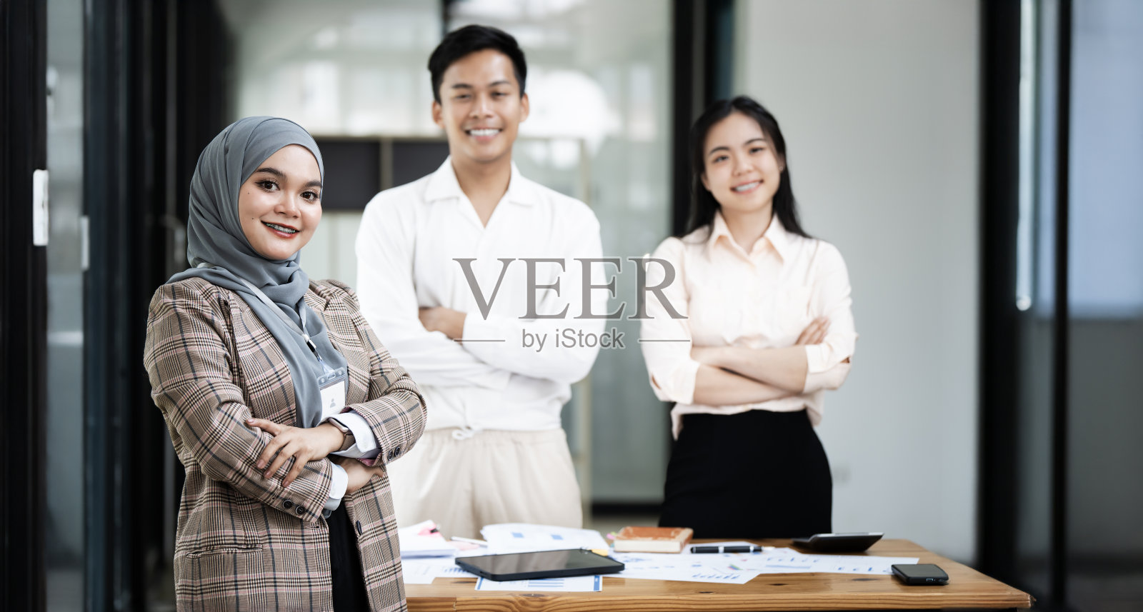 穿着传统头巾的年轻女子与同事站在办公室的肖像。对着镜头微笑照片摄影图片