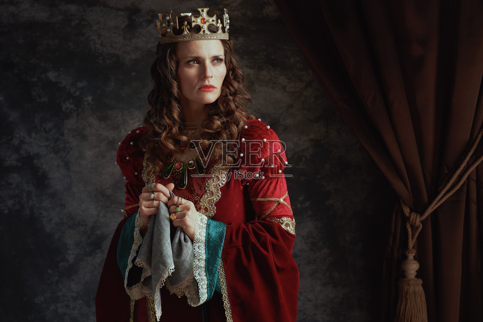 穿着红色中世纪服装、拿着手帕、沉思的皇后照片摄影图片