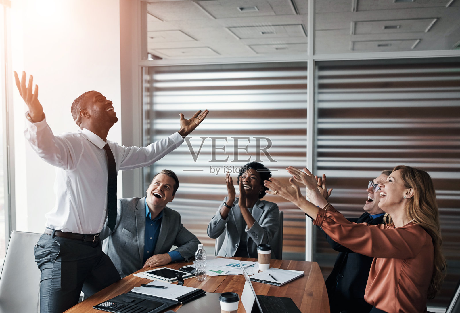 办公室庆祝时，商界人士用掌声或赞美的方式表扬男领导在财务上、表现上或取得的成功。好消息，获胜者或兴奋的会计团队为销售利润或目标欢呼照片摄影图片