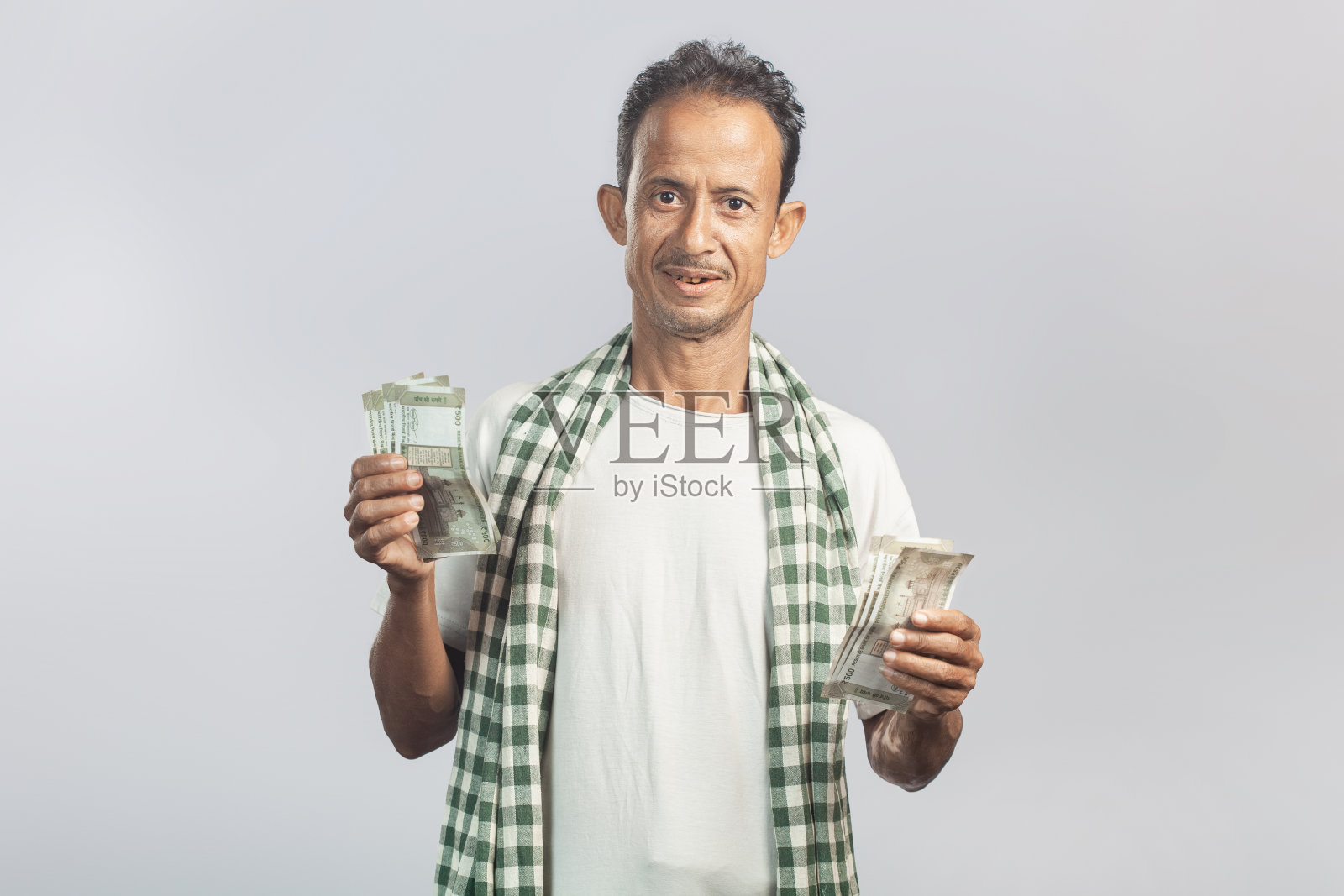 一名印度老人脸上露出愉快的表情，手里拿着卢比纸币照片摄影图片