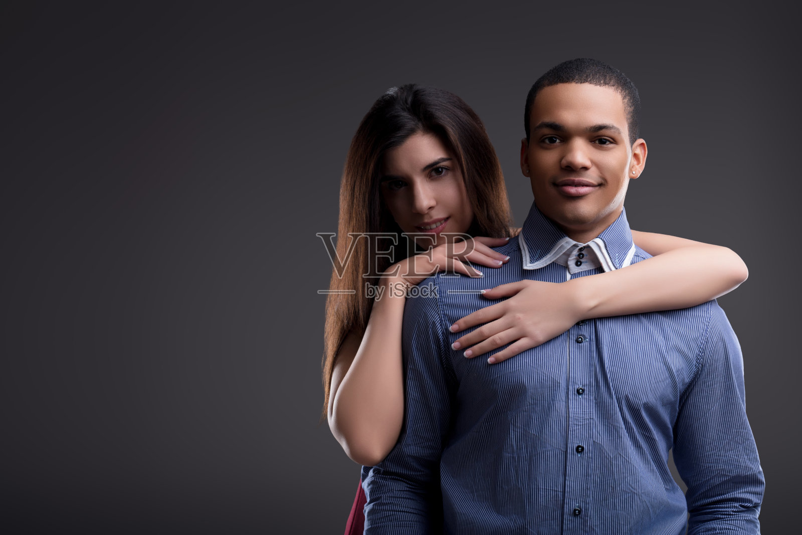 年轻夫妇在灰色背景上拥抱照片摄影图片