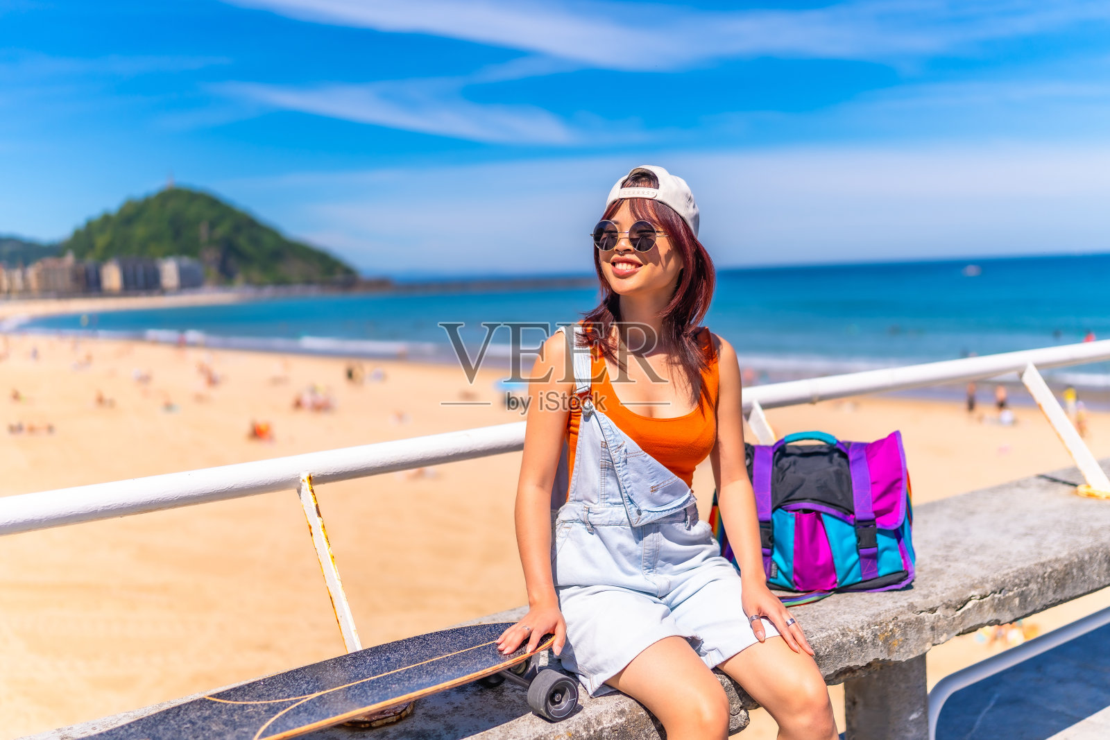 一个亚洲女人拿着滑板坐在人行道上照片摄影图片