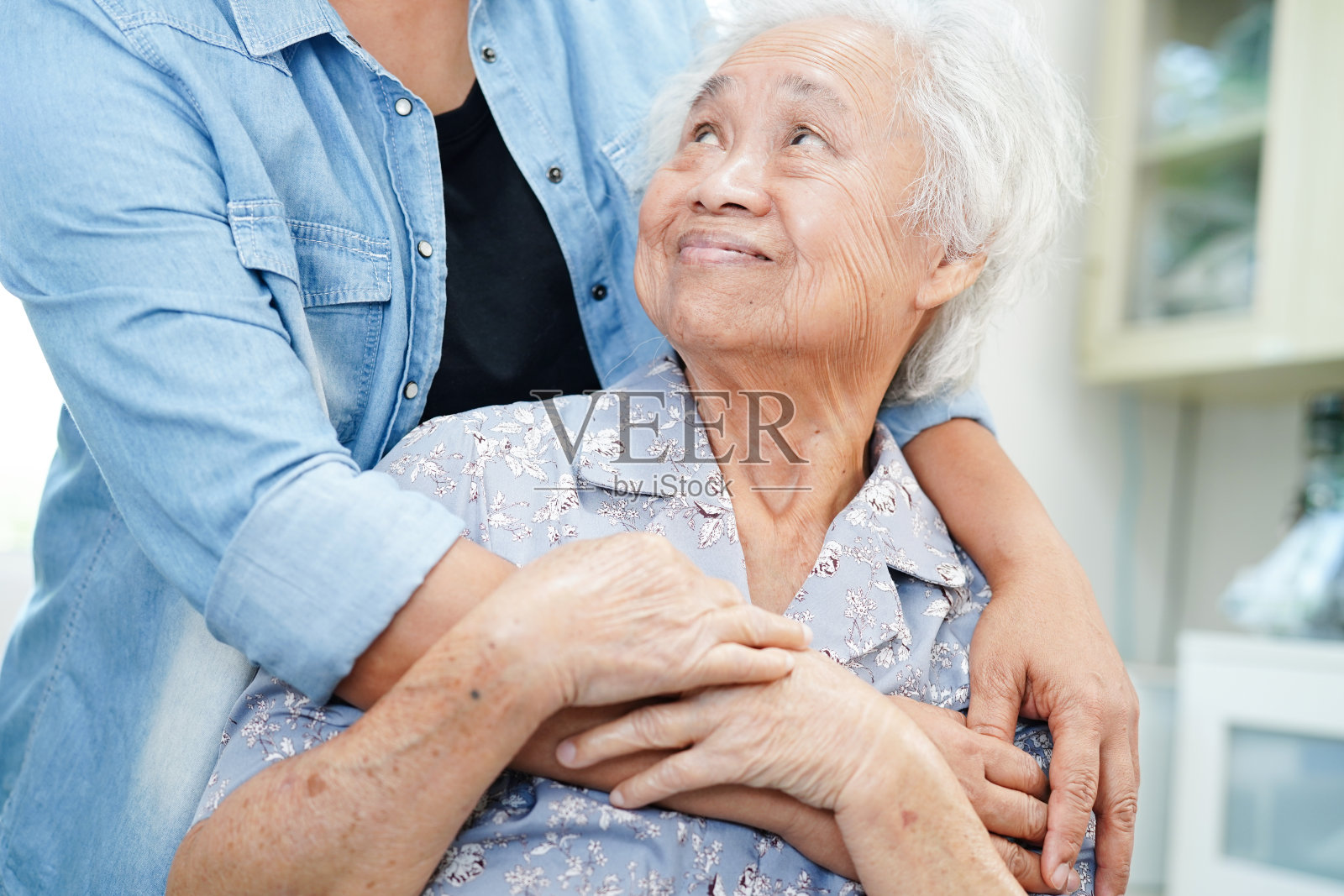 照顾、帮助和鼓励门诊医院的亚洲老年妇女患者。照片摄影图片