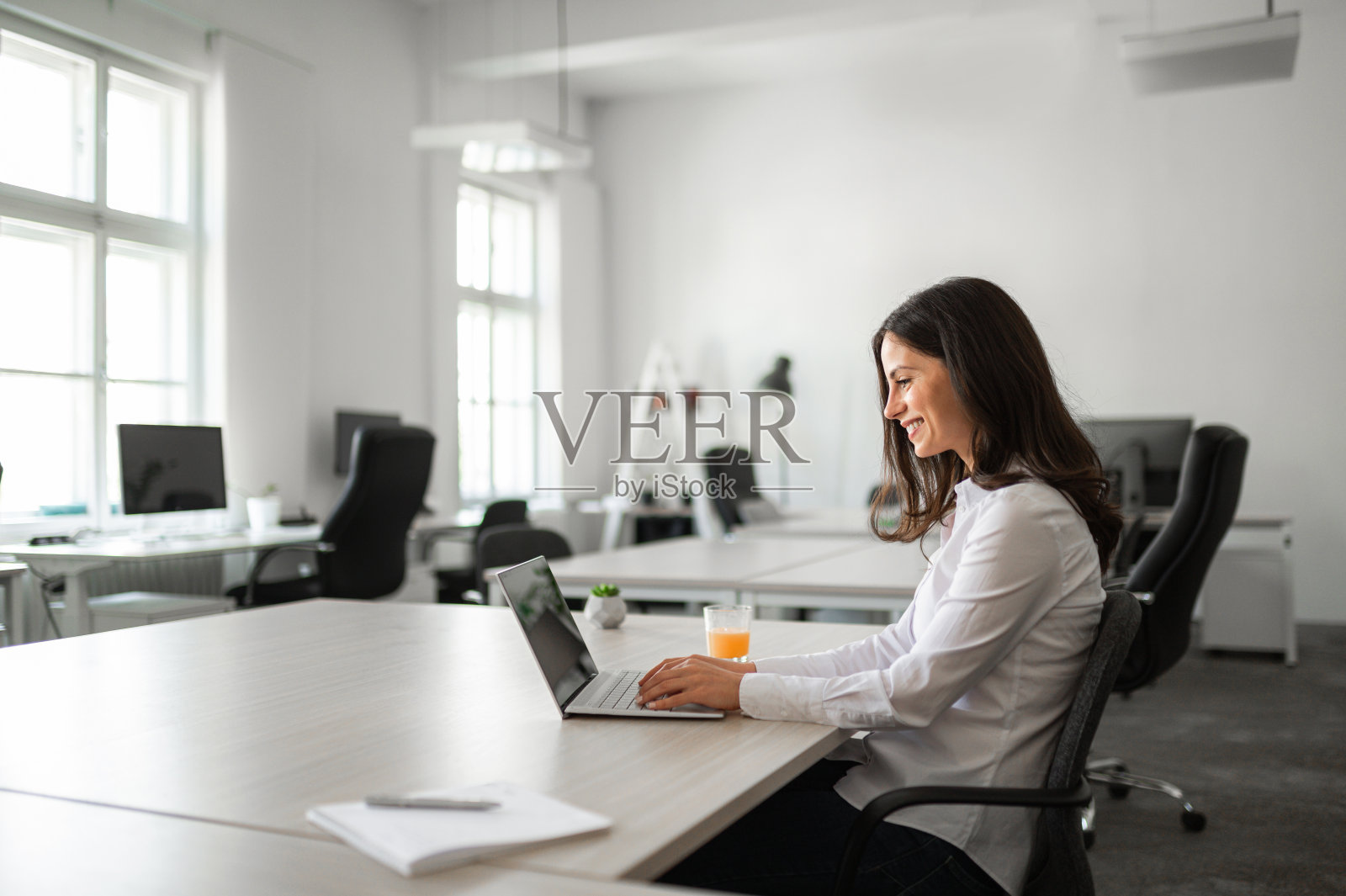 现代联合办公办公室中女性商务人士在办公桌前工作的广角镜头照片摄影图片