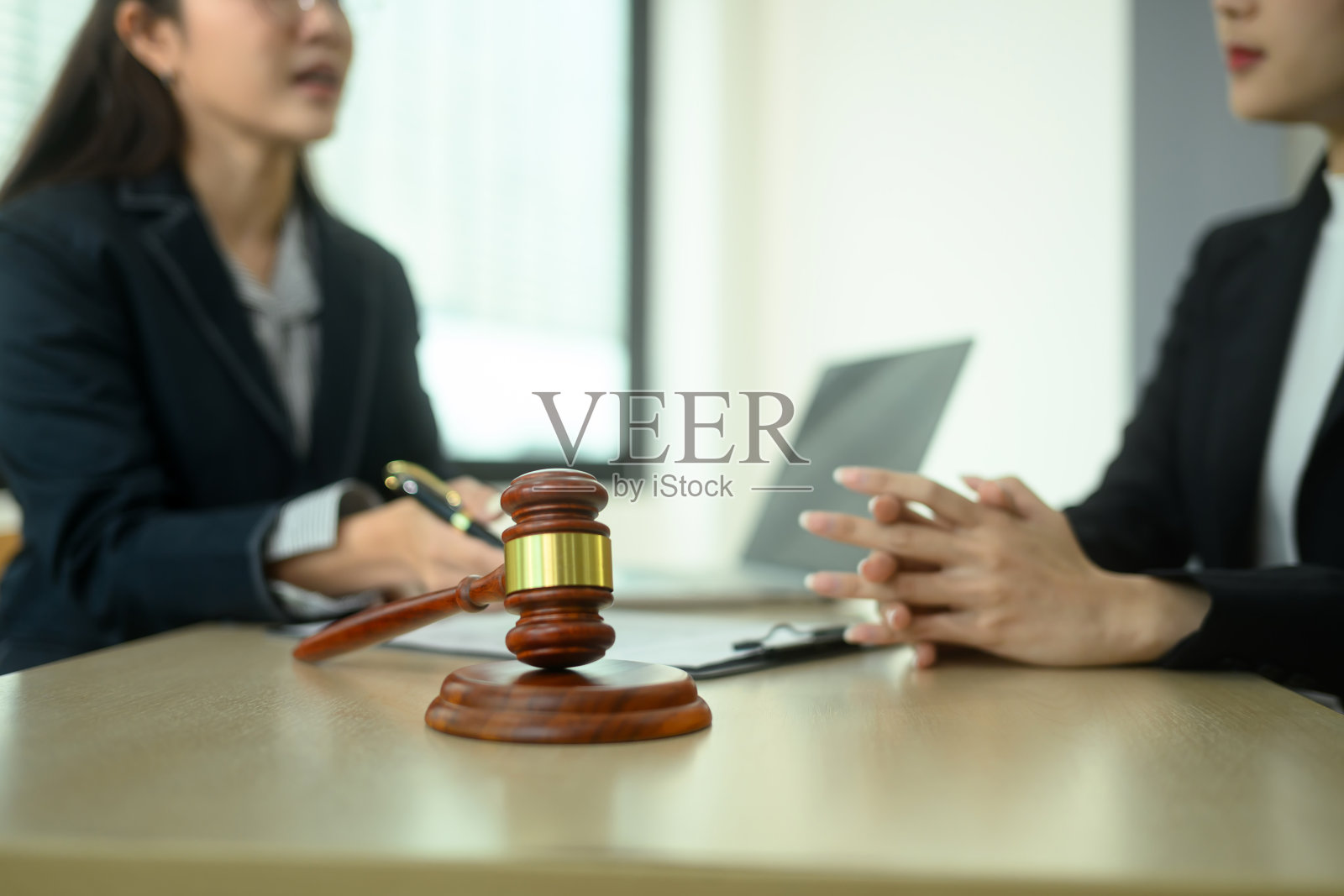 律师在背景中为女性客户提供咨询，木桌上的法官 gavel 与律师和司法概念照片摄影图片