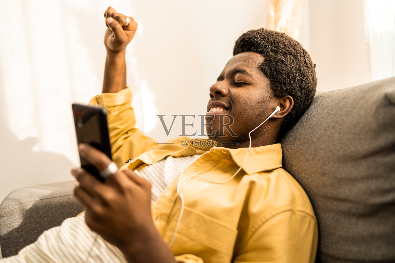 侧视图年轻的非洲裔美国人听音乐和微笑。照片摄影图片