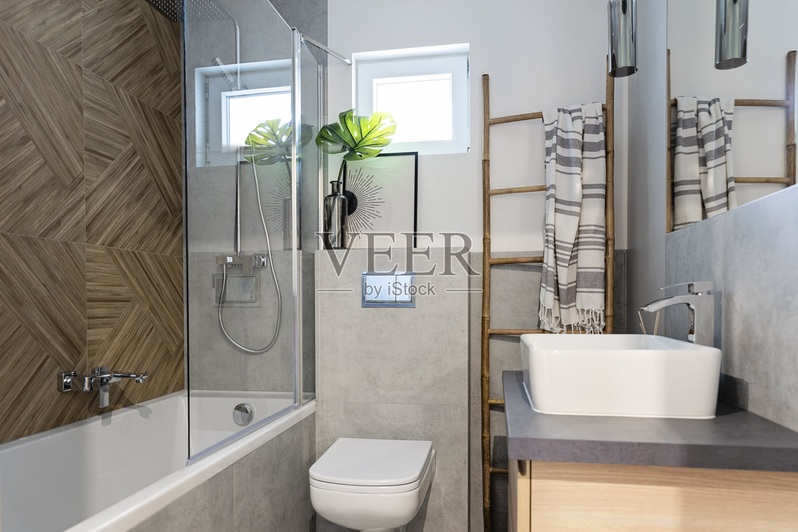 现代浴室的家居内部以蝙蝠、陶瓷浴室水槽和墙上的人字形瓷砖为主。优雅和豪华的新公寓。照片摄影图片