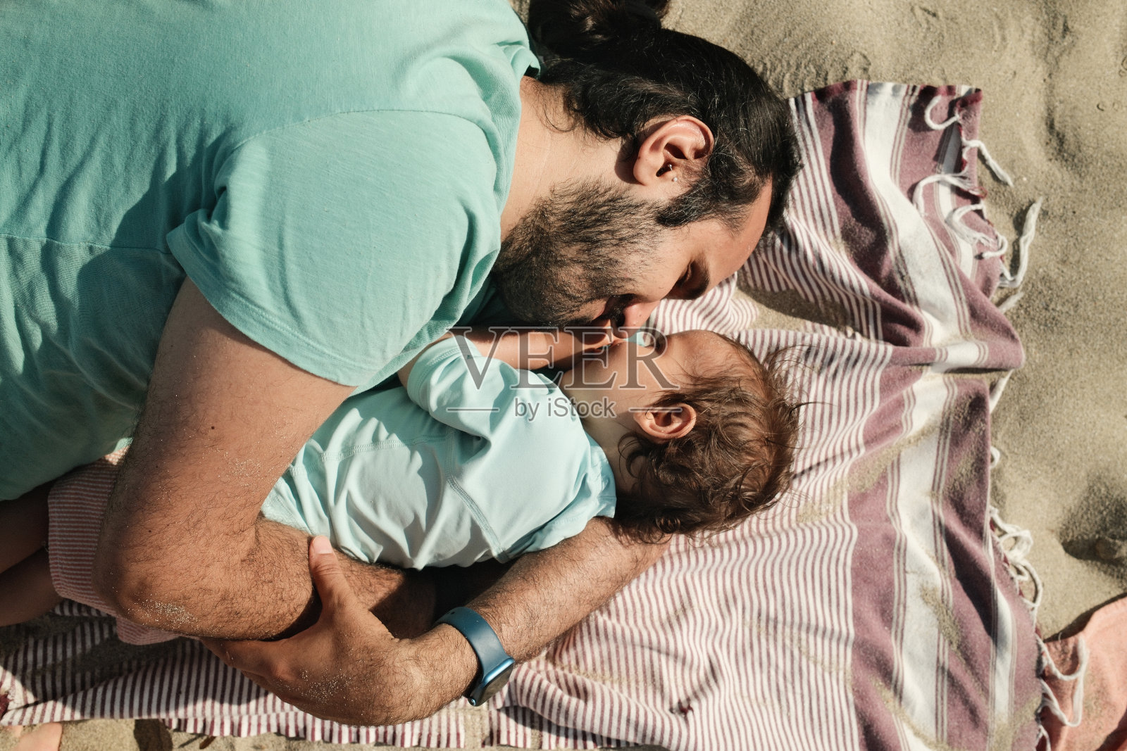 爸爸和宝宝睡在沙滩浴巾上享受暑假照片摄影图片