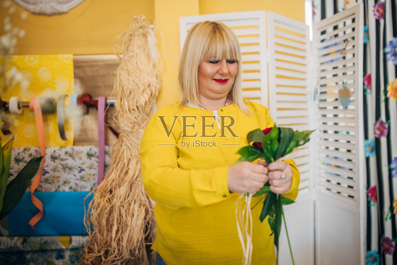 花店里花匠用丝带系着花束。照片摄影图片