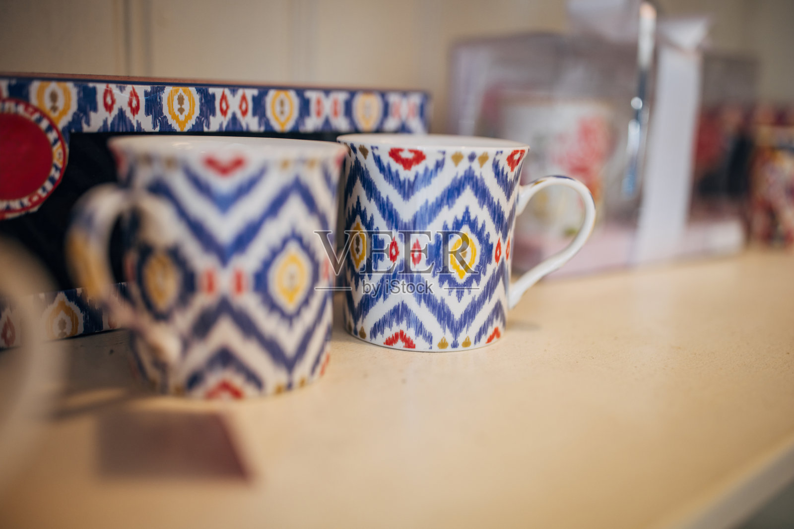木制架子上展示的两个彩色图案马克杯照片摄影图片