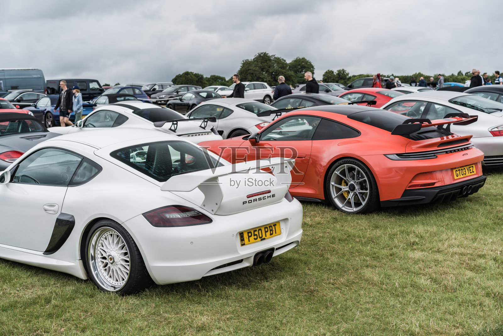 一辆白色的保时捷Cayman和一辆橙色的保时捷911 GT3在汽车展会上展出照片摄影图片