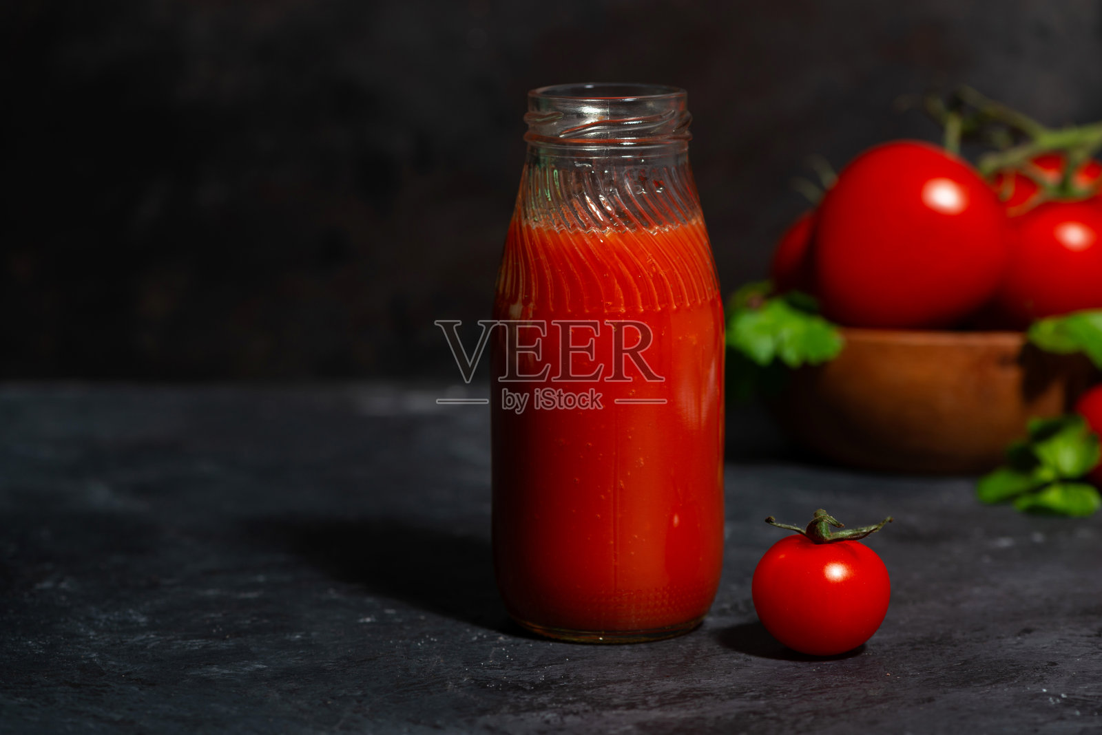 一瓶新鲜的番茄汁，背景是黑色的照片摄影图片