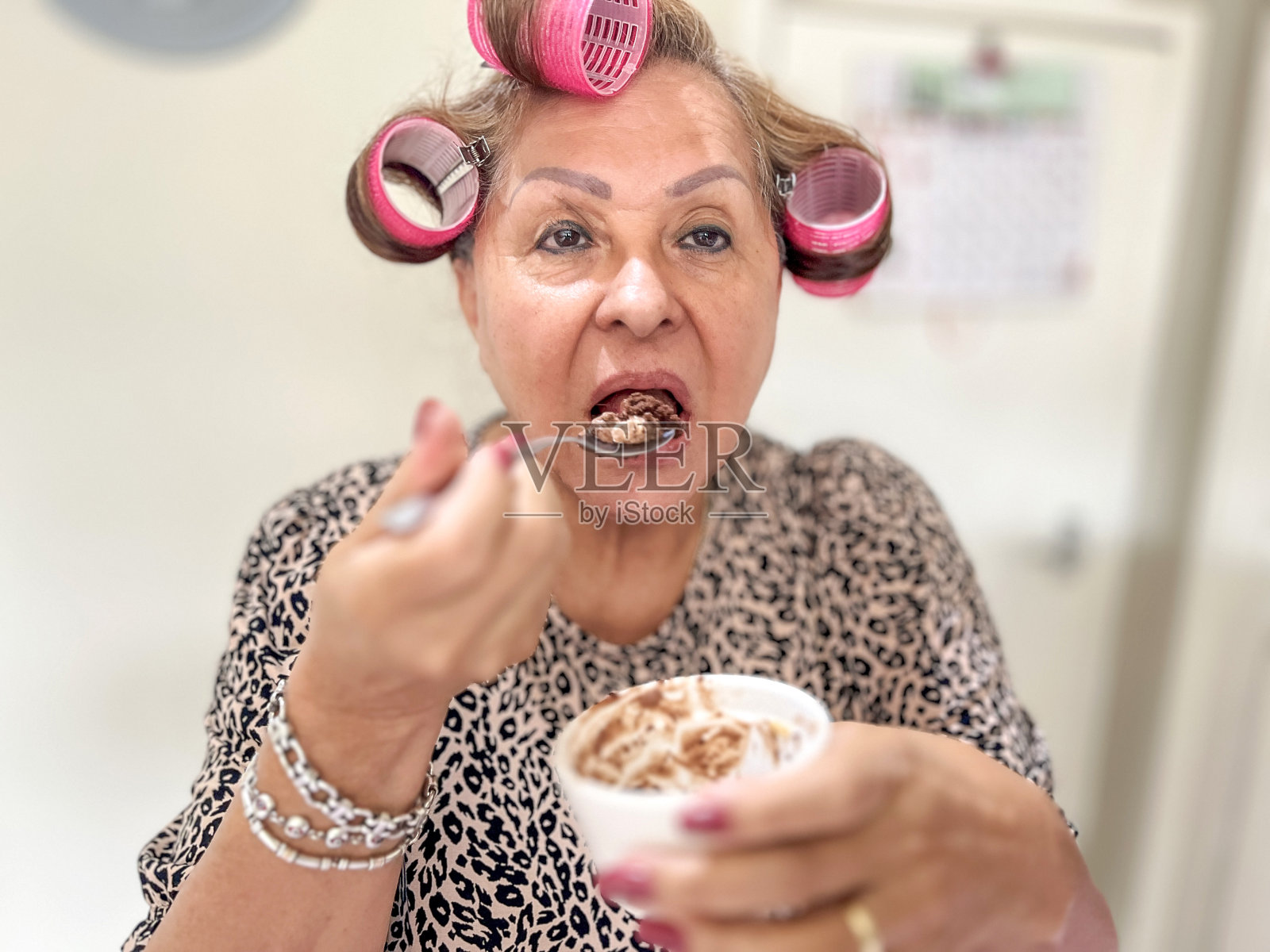 西班牙裔老妇人在家吃冰淇淋照片摄影图片