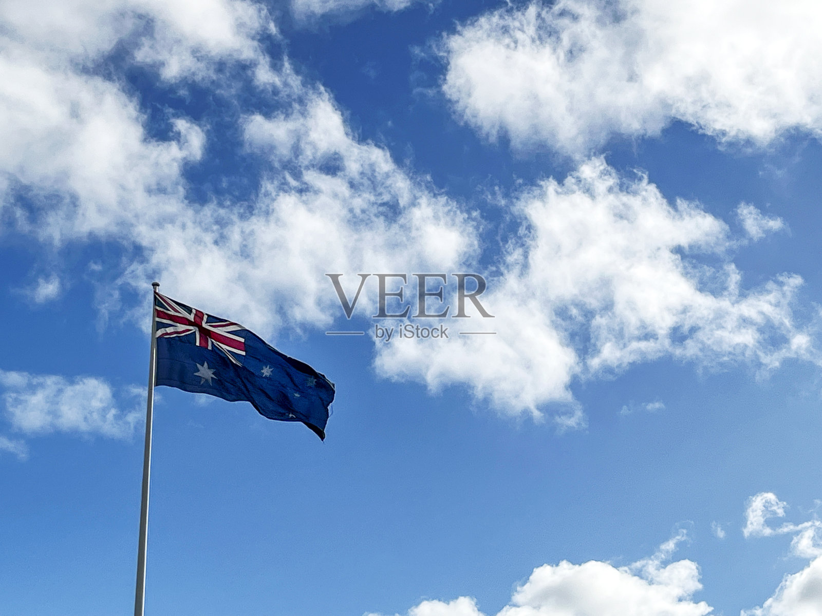 澳大利亚国旗映衬着白云飘飘的蓝天照片摄影图片